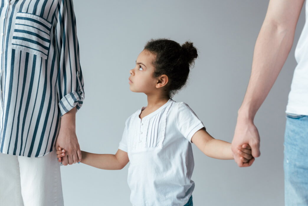 child holding hands with divorced parents