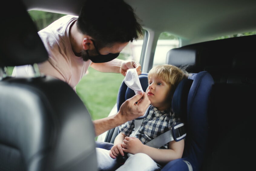 interstate custody - father putting mask on child in car seat